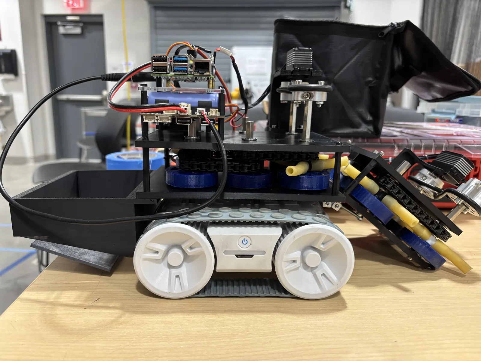 A custom autonomous tracked rover with a single-board computer and wiring on a workbench